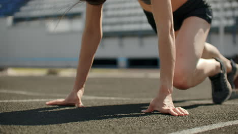 Una-Joven-Atleta-Delgada-Está-En-Posición-De-Comenzar-A-Correr-En-Las-Almohadillas-De-La-Pista-En-Cámara-Lenta